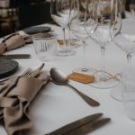 A sophisticated table setup featuring glasses, utensils, and napkins on a white tablecloth.