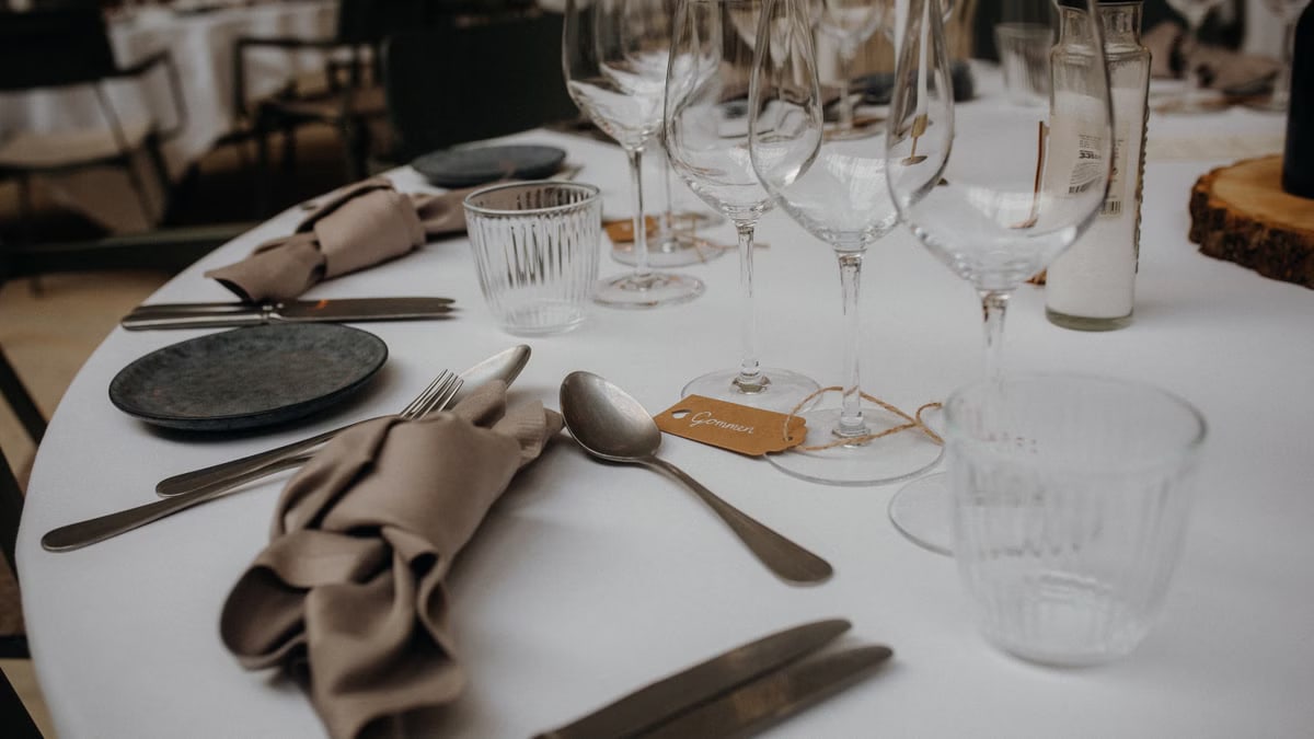 A sophisticated table setup featuring glasses, utensils, and napkins on a white tablecloth.